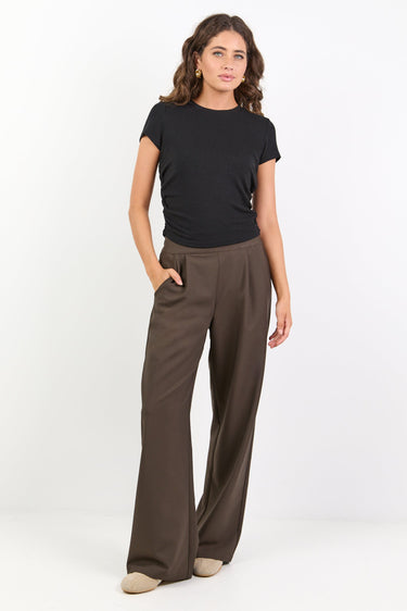 Woman wearing a black t-shirt and brown wide-leg pants on a white background