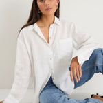 model wears a white linen shirt with blue jeans