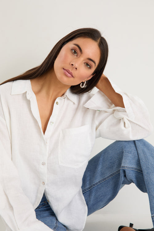 model wears a white linen shirt with blue jeans