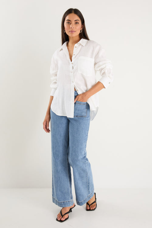 model wears a white linen shirt with blue jeans