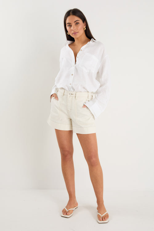 model wears a white linen shirt with blue jeans