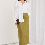 model wears a green skirt and white shirt