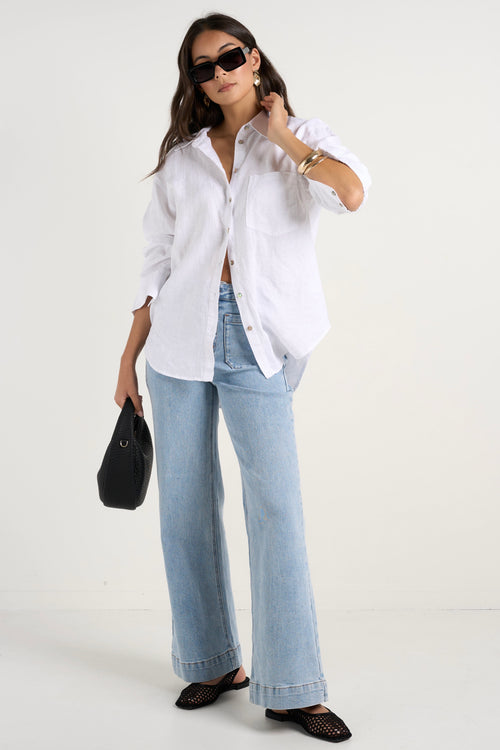 Model wears white linen shirt and light blue jeans