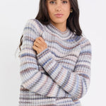 Woman wearing a striped sweater and blue jeans on a white background