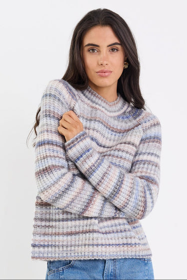 Woman wearing a striped sweater and blue jeans on a white background