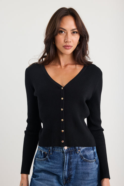 Woman wearing a black cardigan with button details on a white background