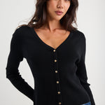 Woman wearing a black cardigan with gold buttons on a white background