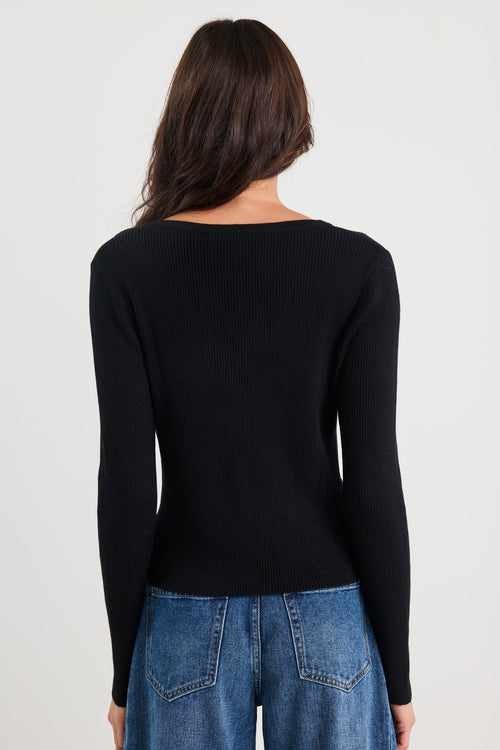 Person wearing a black long-sleeve top and blue jeans on a white background
@col_pattern
