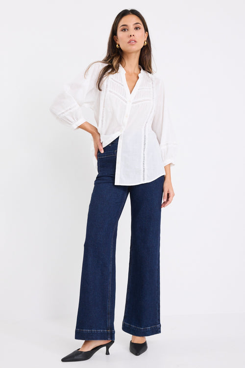 women wears a white blouse with dark blue jeans