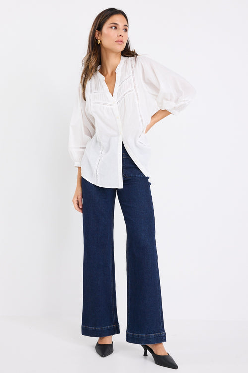women wears a white blouse with dark blue jeans