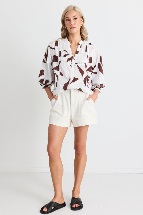 model wears white a brown patterned button down shirt