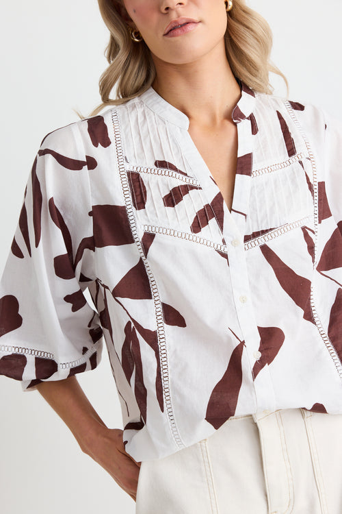 model wears white a brown patterned button down shirt