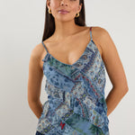 Woman wearing a strappy blue floral scarf-print top with ruffle detailing, styled with indigo jeans.