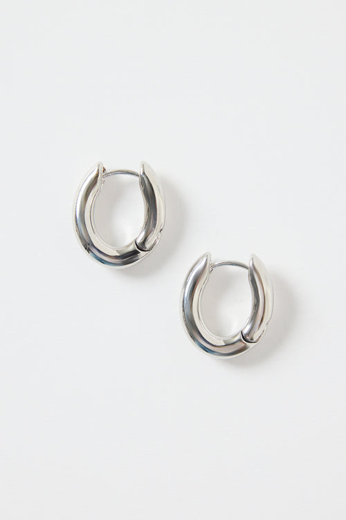 A pair of small oval-shaped wavy rhodium hoop earrings photographed on a clean white background.