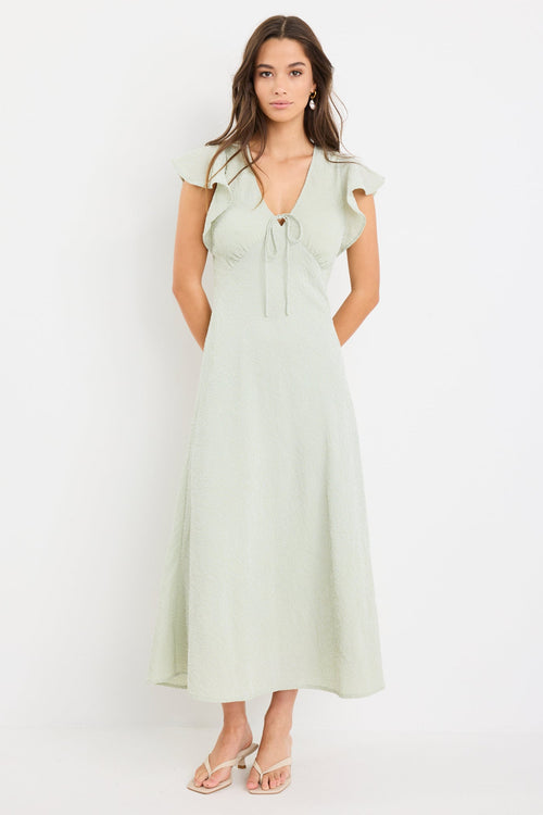 Woman wearing a sage green gingham midi dress with flutter sleeves and keyhole tie neckline.