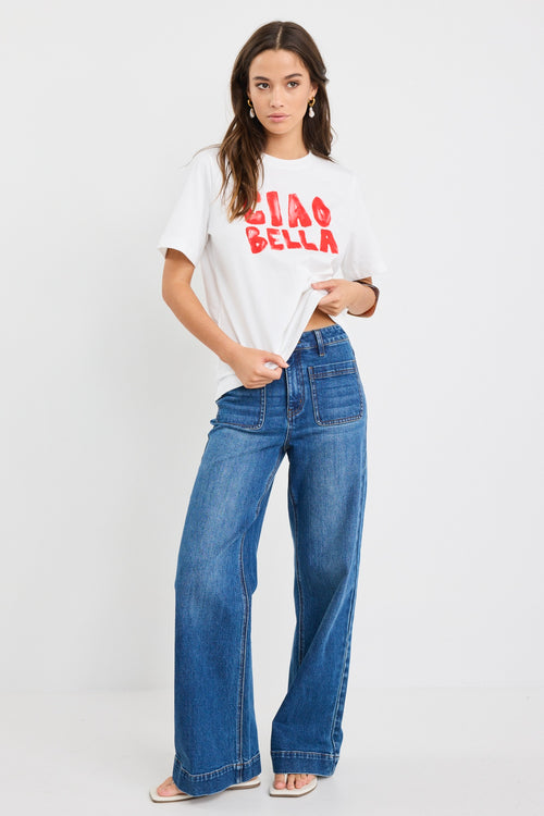 The model wears a white t-shirt with red graphic text and blue jeans