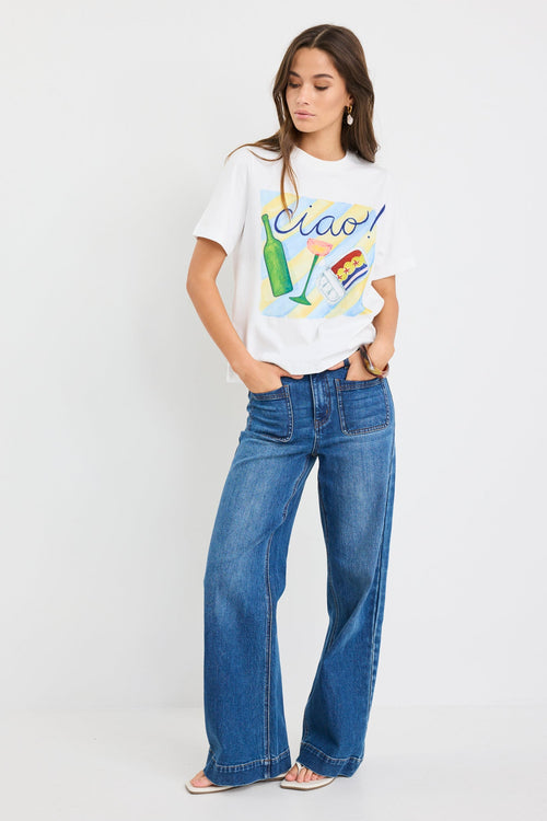 Woman wearing a white t-shirt with colorful graphics and blue jeans on a white background