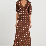 Woman wearing a brown polka dot dress on a white background