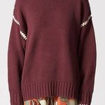 Person wearing a maroon sweater and floral-patterned pants on a white background