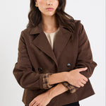 Woman wearing a brown coat with plaid lining on a white background