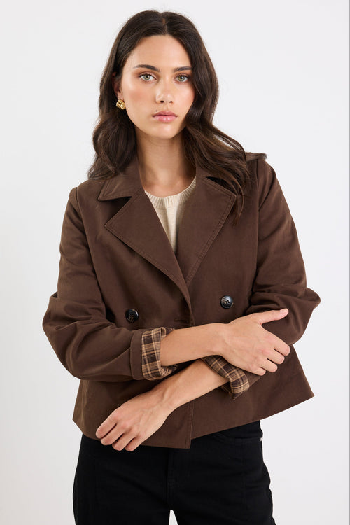 Woman wearing a brown coat with plaid lining on a white background