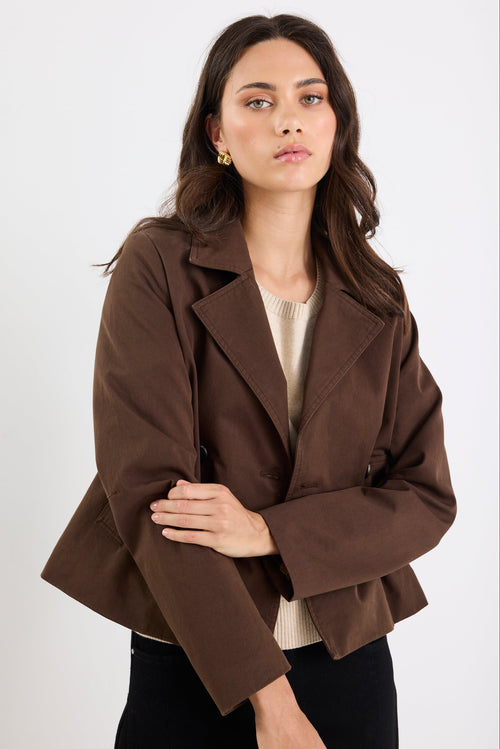 Woman wearing a brown coat against a white background
