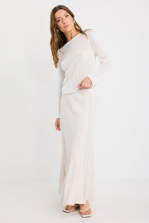 Woman wearing an ivory crochet knit jumper with boat neckline and long sleeves, styled with a natural skirt.