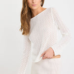 Woman wearing an ivory crochet knit jumper with boat neckline and long sleeves, styled with a natural skirt.