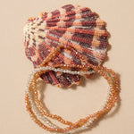 Shell with beaded bracelet on a beige background