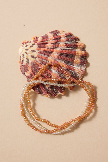 Shell with beaded bracelet on a beige background