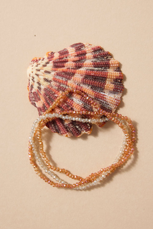 Shell with beaded bracelet on a beige background