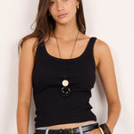 A woman modeling a black sleeveless tank top and light-wash wide-leg denim culottes with a black belt, standing against a plain off-white studio background.