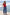 A woman stands on a concrete pier by the ocean wearing a red tank top, wide-leg blue jeans, and black sandals. The background shows blue water and white waves.
