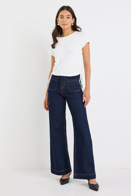 Woman wearing a white top and dark blue jeans on a white background