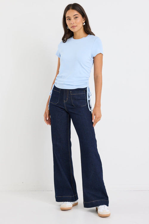 Woman wearing a light blue t-shirt and dark blue jeans on a white background