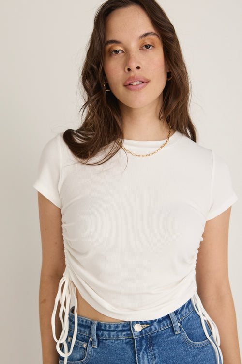 Model wears a white rib top with jeans