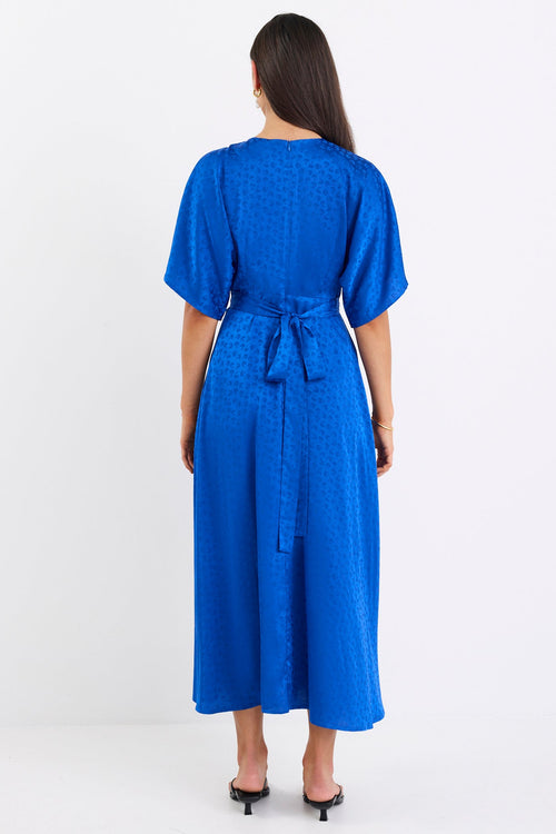 Woman wearing a blue dress with a belt on a white background