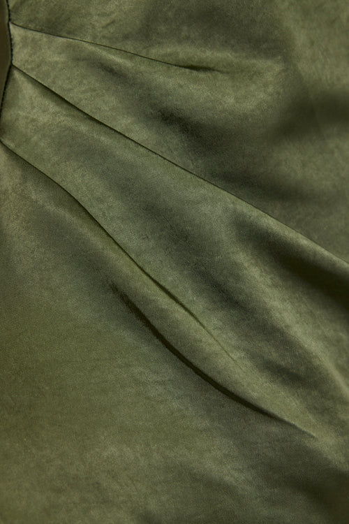 A close-up of olive green draped fabric with soft folds and a slightly matte texture.