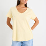 Woman wearing a yellow v neck tee and blue jeans