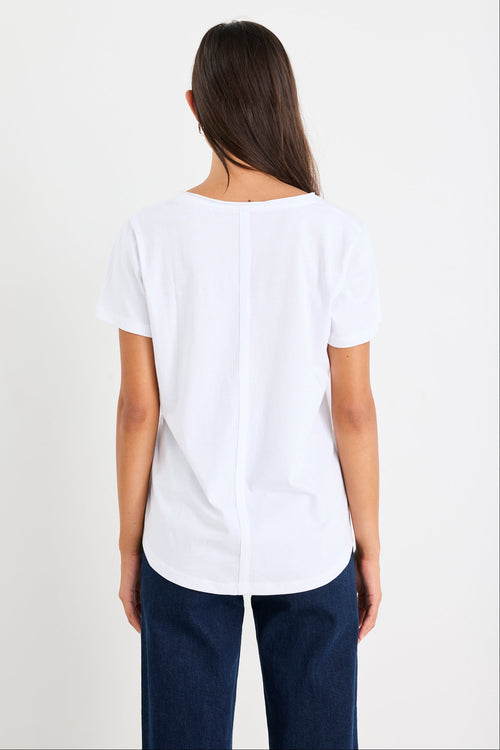 Woman wearing a white v neck top and dark blue jeans