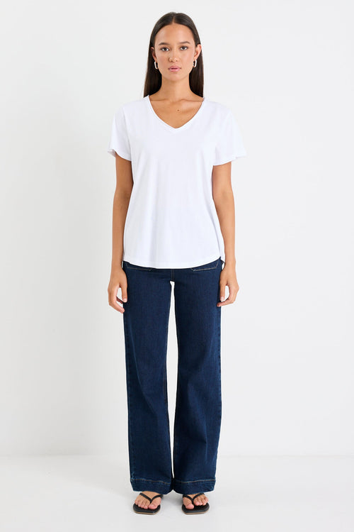 Woman wearing a white v neck top and dark blue jeans