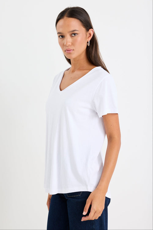 Woman wearing a white v neck top and dark blue jeans