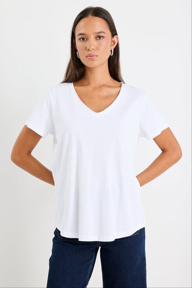 Woman wearing a white v neck top and dark blue jeans