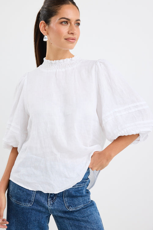 model wears a white linen blouse with dark blue jeans