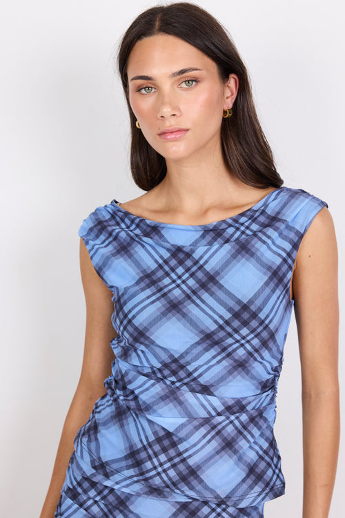 Woman wearing a blue plaid top against a white background