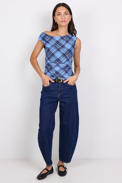Woman wearing a blue plaid top and dark blue jeans on a white background
