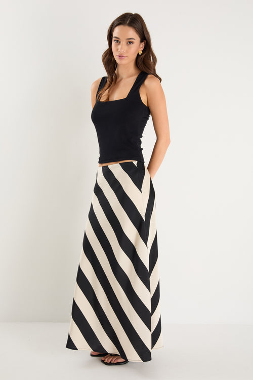 model wears a black and white stripe maxi skirt with a black tank top 