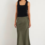 the model wears a khaki green maxi skirt with a black tank top