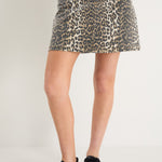 A model wears a leopard print mini skirt with a rigid denim texture and zip fastening, styled with a black sleeveless top.