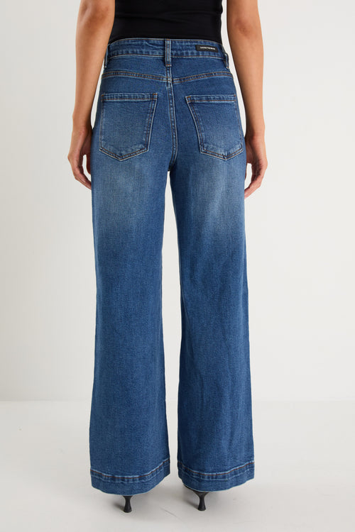 model wears  dark blue wide leg jean with a black tank top